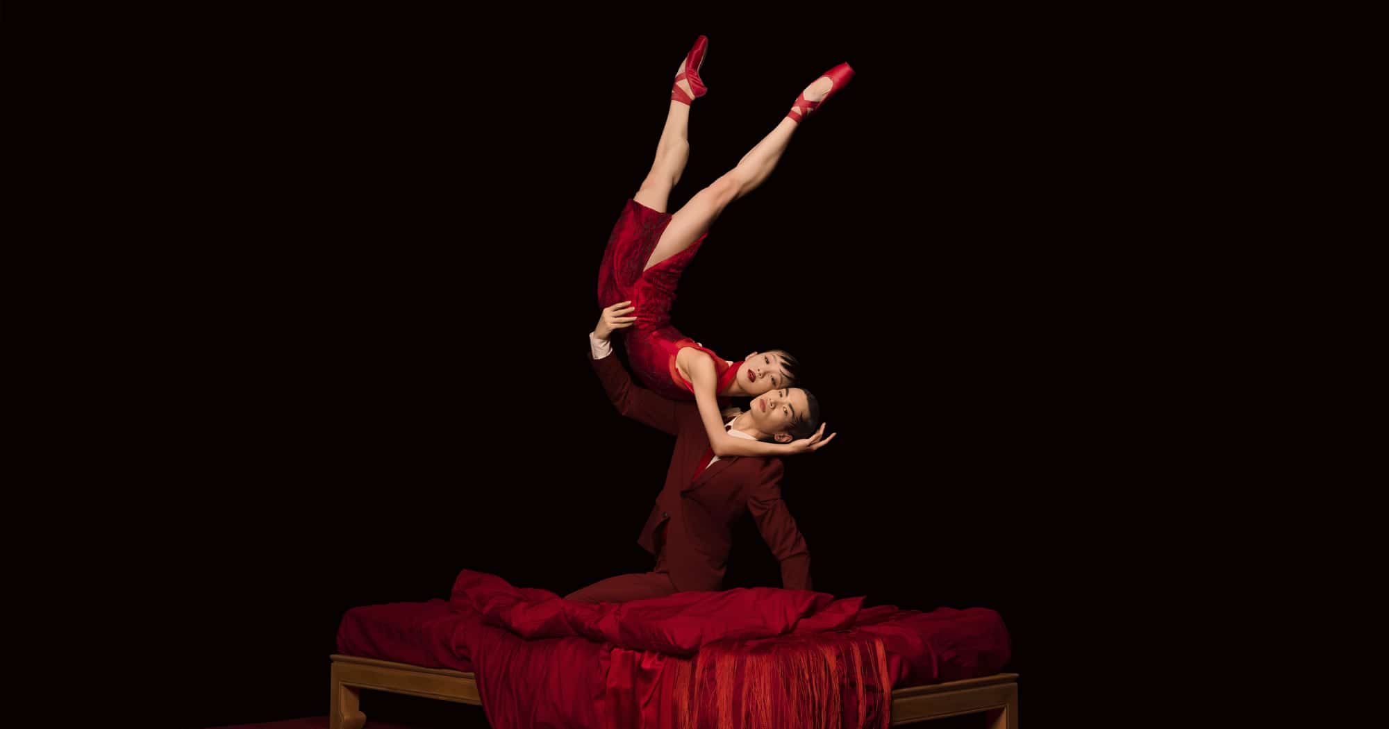 Two dancers from the Hong Kong Ballet perform on a red bed
